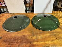 Top view of two green enamel lamp shades showing different diameters and colors, both with fitting holes at center top