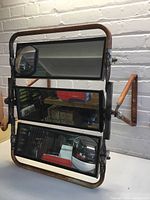 Front view of the steampunk mirror showing three adjustable rectangular mirrors mounted in a rusted tubular metal frame with angular support arms on the sides