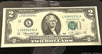 Full front view of the United States $2 banknote showing serial numbers, Treasury seal, Thomas Jefferson portrait, and denomination.