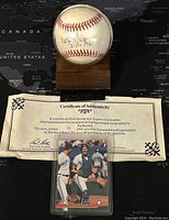 Baseball in display case with certificate of authenticity and trading card underneath on black background with map design
