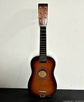 Full front view of the 23-inch brown basswood acoustic guitar showing the entire body and neck against a white background.