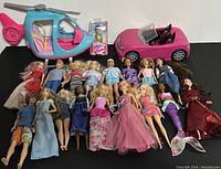 Overview of all 20 items laid out including 18 dolls, a pink convertible car, a helicopter, and packaged Barbie figure