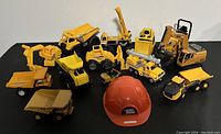 All construction vehicles and hard hat arranged for viewing, showing size and variety.