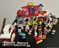 Full overview photo of the lot showing the red barn playset, multiple figures including animals and humans, small vehicles, and accessories arranged on a black surface.