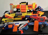 Full view of the assortment of Nerf toys showing multiple styles and colors with various magazines and clips included