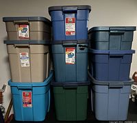 Stacked Rubbermaid plastic storage containers in various colors and sizes, showing front labels and lids.