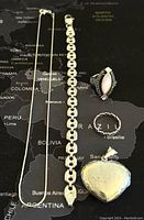 All items displayed together on a map background showing necklace, bracelet, two rings, and heart-shaped pendant.