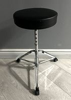 Front view of the drum stool showing round padded seat and tripod base with anti-slip feet