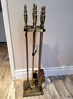 Full view of the fireplace tool set arranged with all tools in the holder, showing the brass handles and base.