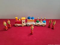 Photo of the children's wooden toy set showing 3-car train with assorted blocks and 5 wooden clown figurines arranged around the train.