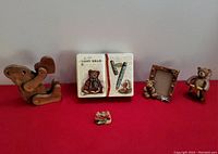 Photo of the full assortment of children's teddy bear themed decor including wooden bears, photo frame, ceramic book figurine, tin, and small animal figurines.