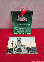 Photo of the 1988 collectible pewter ornament of St. Andrew's Presbyterian Church displayed on its green informational card alongside the 1903 colorized postcard.