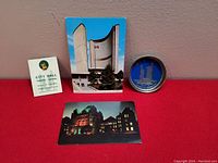 Lot showing all items: City Hall pin dish, City Hall lapel pin on card, daytime postcard of Toronto City Hall, and nighttime postcard of Parliament buildings.