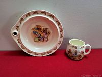 Warming dish and cup shown side by side on red background, warming dish has Bunnykins rabbit border and colored Bunnykins scene in center, cup has matching Bunnykins scene and handle.
