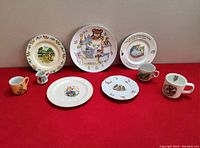 Full group of eight children's dishes including six plates and two mugs displayed on neutral backdrop