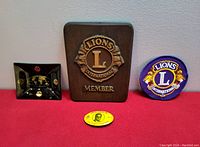Full lot showing all four items: wooden plaque, glass dish, embroidered patch, yellow pinback
