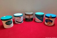 Full view of all 5 tobacco tins including two plastic tins (Craven Menthol and Williams) and three metal tins (two Player's and one MacDonald's).