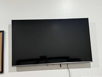 Flat front view of a 44-inch LG Smart TV mounted on a white wall, showing the black screen and slim bezel.