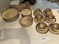 Full set arranged on table showing stacked large plates, small plates, bowls, and teacups with saucers.