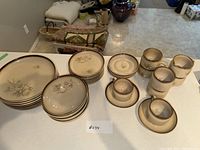 Overview of all dinnerware pieces arranged on a table, showing plates, bowls, cups, saucers, and creamer pitcher.