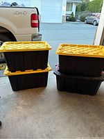 Four tough totes stacked in pairs on a garage floor; three HDX brand with yellow lids and one Husky brand tote forming bottom layer on one stack.