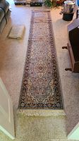 Full view of the long runner rug laid out on carpet.