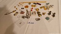 Wide shot of all the assorted costume jewelry laid out on white cloth background. Includes earrings, necklaces, pins and bracelets in various styles and colors.