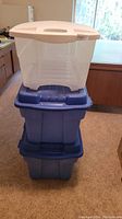 Three Rubbermaid storage bins stacked: two large blue totes and one smaller clear bin with white lid on top.