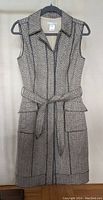 Front view of the sleeveless herringbone tweed dress with belt and flap pockets.