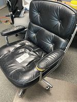 Front angled view of black tufted leather office chair on chrome base.