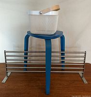 Photo showing the full lot: blue stool supporting white basket with wooden handle and a horizontal silver metal shelf (Grundtal) placed on the floor behind.
