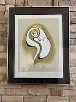 Framed abstract art print hanging on brick wall, showing composition and framing details.