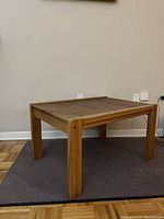 Side and partial angled view of the wood coffee table showing leg construction and general wear on finish.