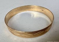 Circular view of bangle showing etched exterior pattern and interior hallmark.