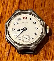 Front close-up of antique DELIA wristwatch showing dial with black and red numerals, and engraved sterling silver octagonal case.