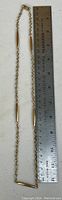Full chain folded in half laid alongside stainless steel ruler showing link pattern and approximate half-length of about 10 inches
