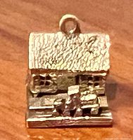 Close-up image of the gold charm showing detailed roof texture, windows, and the tiny moveable train figure on track in the front.