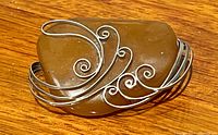 Top down view of amber brooch showing smooth polished amber and silver wire wrap design