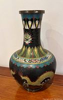 Front view of the vintage brass cloisonne Chinese dragon vase showing colorful dragon and floral designs on black background with brass rim.
