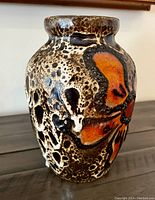 Front view of vase showing detailed textured glaze and large orange flower design.