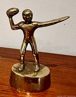 Front and angled view of the vintage solid brass football player statue displaying the throw pose and details.