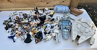 Full lot of Star Wars vintage figures scattered on white table with several vehicles including Millennium Falcon and Imperial Shuttle