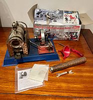 Vintage Wilesco D5 steam engine model with original box and accessories on wooden table.