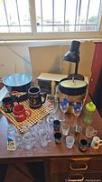 Photo of Broncos ice bucket, mugs, steins, shot glasses, mini mason jars, lamp, CDs, and wicker placemats on wooden table