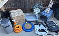Overview photo showing various items including cat litter box, cat toys, animal carrier, backpacks, waste basket, spray bottle, and baskets on outdoor patio