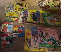 Photo of assorted children's vinyl records spread on carpet, includes Bugs Bunny, Aristocats, Pinocchio, Mickey, Winnie the Pooh cover artwork and three 45 RPM records with colorful illustrated covers.