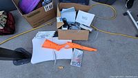 Nintendo Wii system components including console, Wii Fit balance board, orange rifle accessory, and boxed Wii games.
