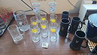 Full lot view showing all 14 items including the Playboy beer steins in front, TAB glasses in middle, and Paulaner and Condor Flats pilsner glasses in back
