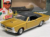 Front and side view of gold 1966 Pontiac GTO die-cast model with black roof inside partially opened box, showing John Force and Castrol branding on packaging.
