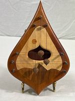 Front view of the wooden door chime showing three pendulums on strings and intricate wood inlay details.